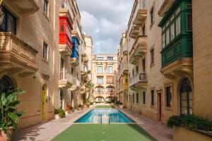 an alley with a swimming pool between two buildings at Il-Kannizzata luxurious Gozo penthouse with sea view & pool in Għajnsielem