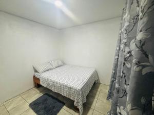 ein kleines Schlafzimmer mit einem Bett und einem Vorhang in der Unterkunft Izzy Blue House in Talamanca