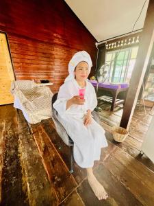 a woman sitting in a chair holding a drink at Ruen Rinna home stays in Surin