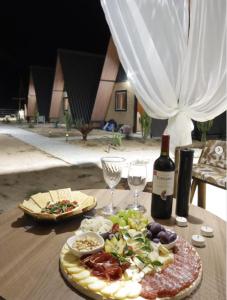 a table with a plate of food and a bottle of wine at Chalés Vale da Luma in Cavalcante