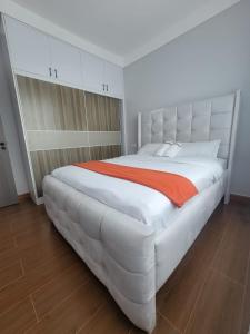 a large white bed with an orange blanket on it at Haven Place 254-near JKIA,SGR with Self-Check in & Free Parking in Nairobi +15 photos