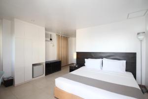 a bedroom with a large white bed and a kitchen at Bluewaves Westcliff Villa in Boracay