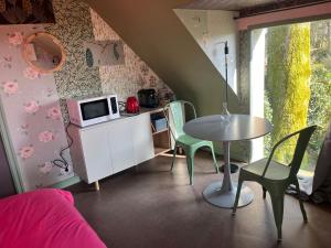 a small room with a table and chairs and a microwave at Escapade de charme à Questembert in Questembert