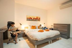 two children sitting in a bedroom with a bed at The Strand Waterfront Apartment with 3 Bedrooms, 4 Bathrooms, Private Garage in Sliema