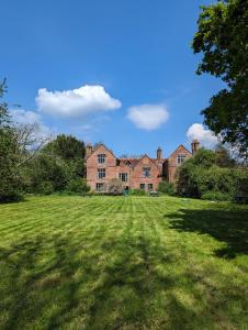 a large house with a grass field in front of it at Old Manor House in Shepperton
