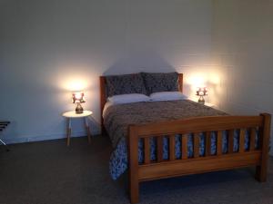 奧馬魯的住宿－阿倫經濟公寓，一间卧室配有一张木床和两盏灯。