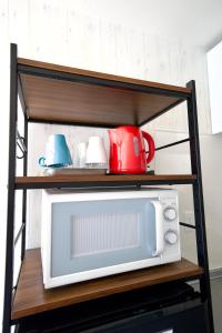 a microwave on a shelf with mugs on it at Guest House Re-worth Yabacho1 402 in Nagoya