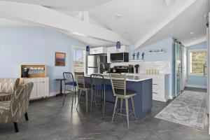 a kitchen with white cabinets and a blue island with chairs at Modern Waterfront Apt with Bay Views in Falmouth