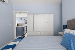 a bedroom with a bed with white cabinets and a kitchen at Modern Waterfront Apt with Bay Views in Falmouth