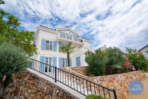 a white house on a stone wall with plants at Rooms Salvia in Cres +64 photos