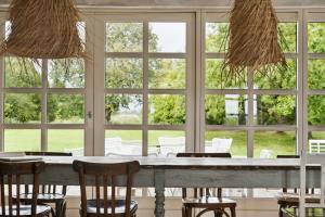 a dining room with a table and chairs and windows at By The Bay A Thatched House Lies So Beautifully in Nørre Åby