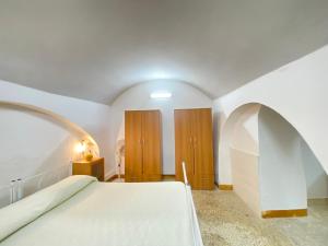 a bedroom with a white bed and wooden cabinets at Lo Scoglio Bianco in Gallipoli