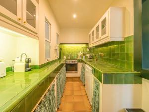 a green and white kitchen with a long counter at Els Tamarells Apartment by 3VILLAS in Fornells +17 photos