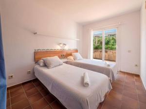 two beds in a room with a window at Els Tamarells Apartment by 3VILLAS in Fornells