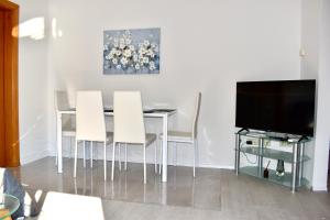 a dining room table with white chairs and a television at Apartmani Cassiopeia in Murine