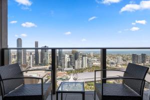 a balcony with two chairs and a glass table at 39th floor luxurious spacious apartment in Melbourne