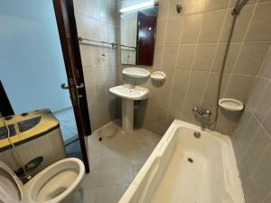 a bathroom with a toilet and a sink and a tub at Your Comfort Starts Here in Ras al Khaimah