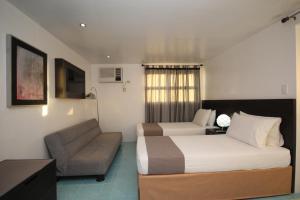 a hotel room with a bed and a couch at Bluewaves Westcliff Villa in Boracay