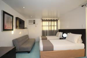 a hotel room with a bed and a couch at Bluewaves Westcliff Villa in Boracay