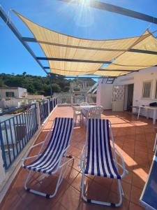 zwei blau-weiße Stühle auf einem Balkon mit Sonnensegel in der Unterkunft Attico 5 in Ustica