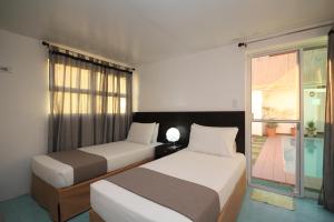 two beds in a room with a window at Bluewaves Westcliff Villa in Boracay
