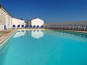 a large swimming pool with blue chairs and chairs at Camping Le Pavillon bleu in L'Aiguillon-la-Presqu'île
