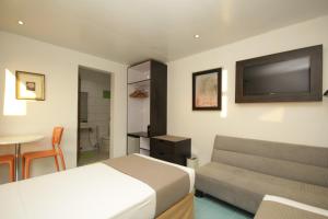 a bedroom with a bed and a couch and a tv at Bluewaves Westcliff Villa in Boracay
