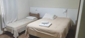 a bedroom with two beds with white sheets and two towels at Cyro Palace Hotel Ltda in Caçapava do Sul