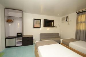a hotel room with two beds and a couch at Bluewaves Westcliff Villa in Boracay