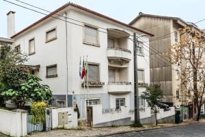 a white building with a flag in front of it at HI Coimbra - Pousada de Juventude in Coimbra