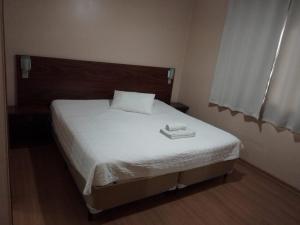a bedroom with a bed with a white sheets and a tray on it at Cyro Palace Hotel Ltda in Caçapava do Sul