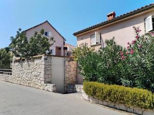 a house with a stone wall next to a street at Apartman David in Postira