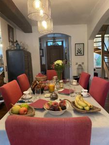 a table with fruit on it with red chairs at LE PRESBYTERE in Chasnay