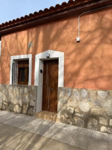 a building with a brown door and a stone wall at Apartamento Villuercas in Cañamero