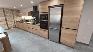 a kitchen with wooden cabinets and a stainless steel refrigerator at Létable de Boissadel in Boisset