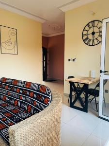 a living room with a table and a clock on the wall at Les Résidences CICA in Ouidah +7 photos