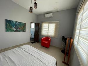 a bedroom with a bed and a red chair at Les Résidences CICA in Ouidah