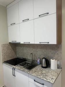 a kitchen counter with white cabinets and a sink at Solis Residence Batumi in Batumi