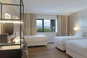 a hotel room with two beds and a window at NH Mendoza Cordillera in Mendoza