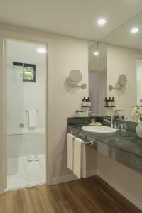 a bathroom with a sink and a shower and a mirror at NH Mendoza Cordillera in Mendoza