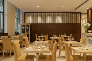 a restaurant with white tables and chairs and a fireplace at NH Mendoza Cordillera in Mendoza