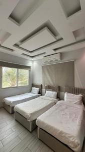 a bedroom with two beds and a large window at درة العروس البرادايس دور علوي عوائل فقط in Durat Alarous