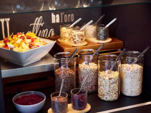 a counter with several jars of granola and a bowl of fruit at B&B HOTEL Rostock-Hbf in Rostock