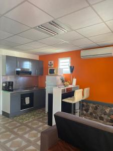 a kitchen with orange walls and a table and chairs at Habitations Amédée in Bouillante +15 photos