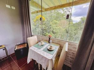 a table and chairs in a room with a window at Pousada All Green - Monte Verde in Monte Verde