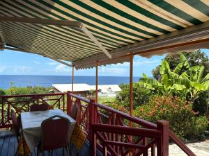 a deck with a table and chairs and the ocean at Habitations Amédée in Bouillante