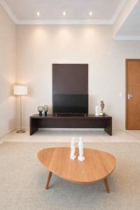 a living room with a table and a flat screen tv at Apê 401 - Central, Garagem e Ar-Condicionado - 2Q in Governador Valadares