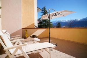 a group of chairs and an umbrella on a balcony at Villa Kappa - disponibili anche camere climatizzate - in LʼAquila