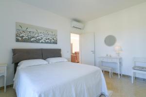 a white bedroom with a white bed and a table at Casa Saveria in Massa Lubrense +20 photos