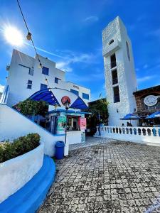 a white building with a clock tower next to a street at Hotel Santorini Doradal in Doradal